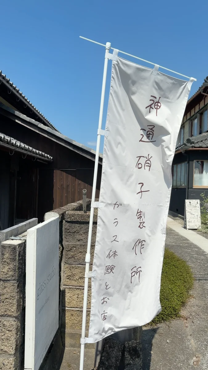 道沿いに立つのぼり。「ガラス体験とお店」とあります（左）／表札はガラスブロック。「神通硝子製作所 + calm life」と彫ってあります（右）