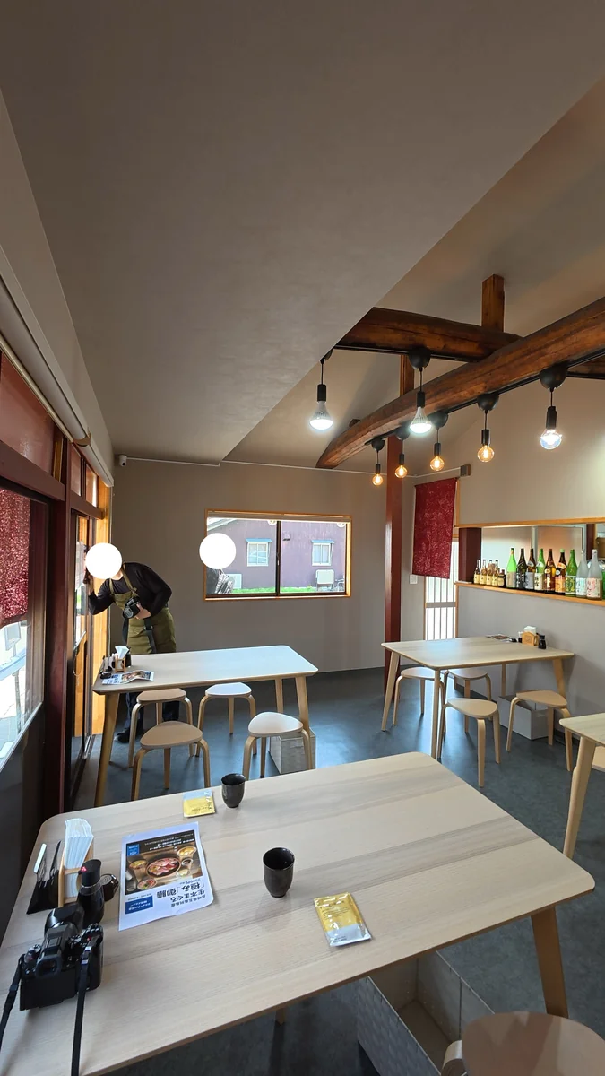 店内。テーブル席が並びます。梁がそのまま見えています(左)/入口の看板。書いてあるのは店名の「幸」だけです(右)