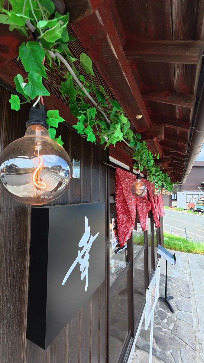 店内。テーブル席が並びます。梁がそのまま見えています(左)/入口の看板。書いてあるのは店名の「幸」だけです(右)